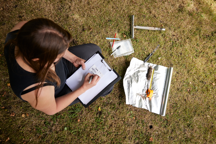 A person with surveying tools making notes outside